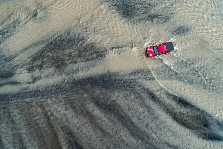 Modified super jeep crossing a glacier river below Eyjafjallajokull on an Iceland volcano tour